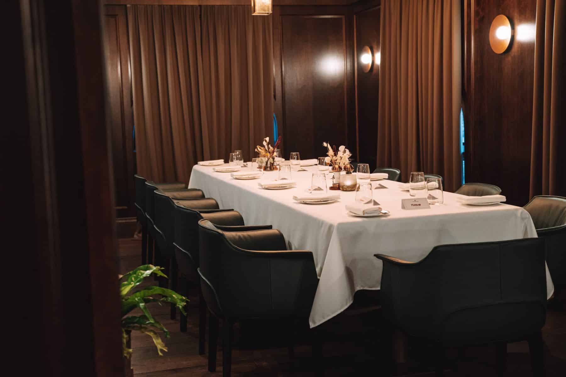 a table with white tablecloth and black chairs