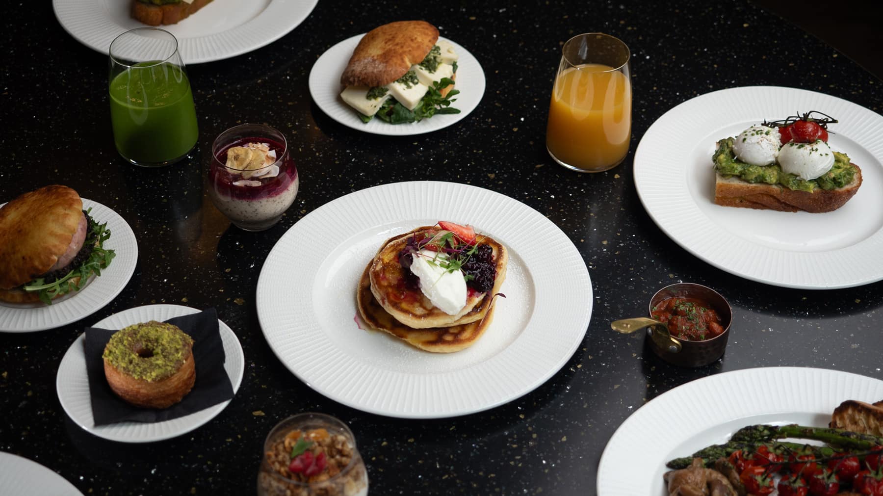 Italian breakfast table at Piazza Italiana with cornetti, poached eggs, avocado toast, fresh juices and espresso